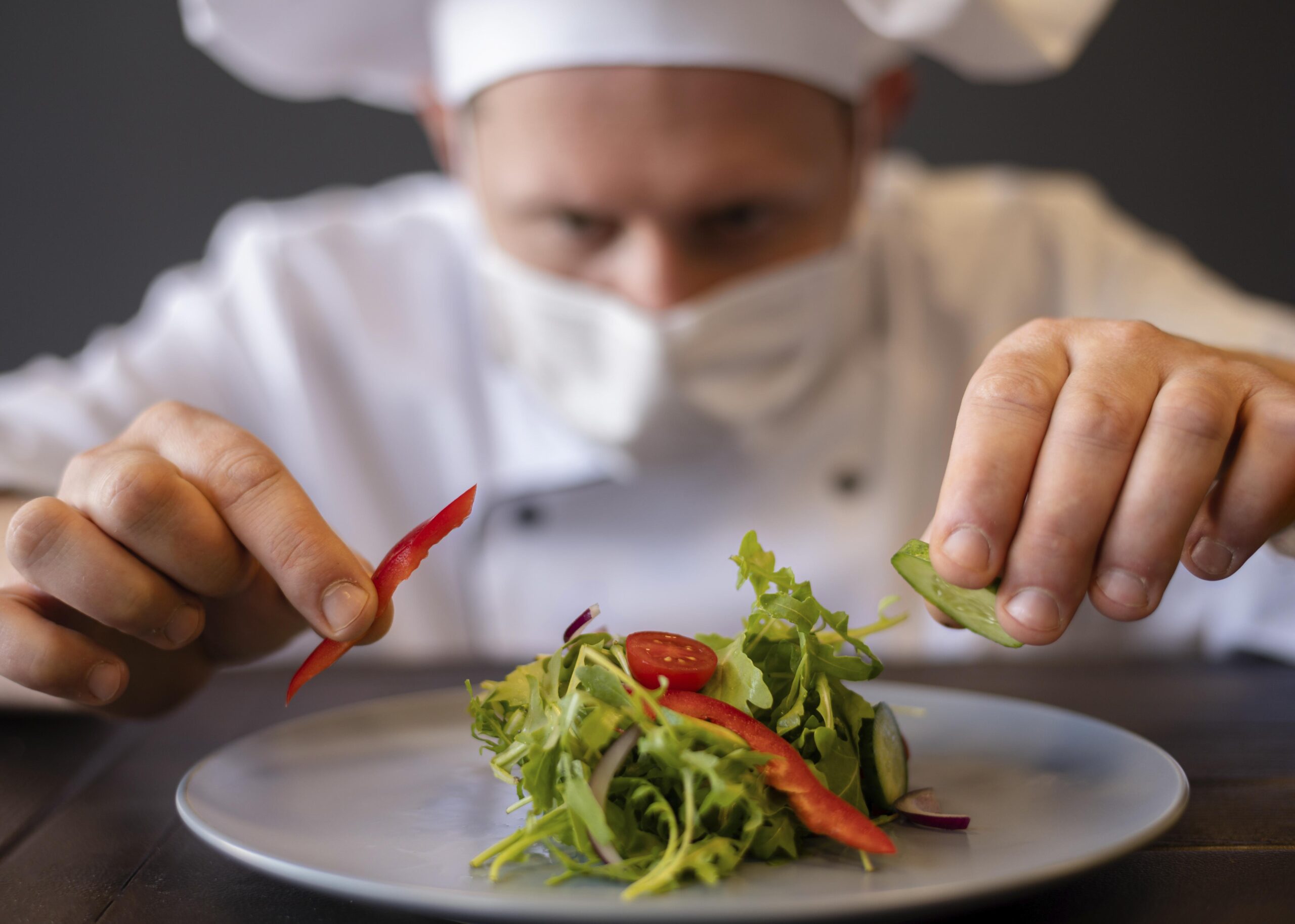 close-up-chef-with-mask-preparing-dish